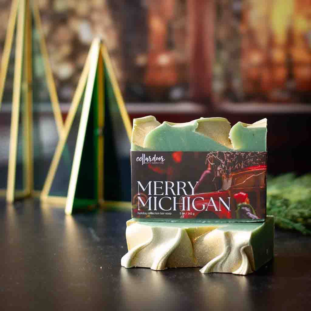Bar of soap with 'Merry Michigan' packaging on a decorative stand with blurred background