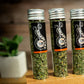 Three Shady Cat Social Club vials of organic catnip on a wooden surface with a blurred background