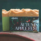 Two rectangular bar soaps in a row, with the front soap wrapped in a dark label reading 'cellardoor' and 'AUTUMN APPLE FEST'. The front soap is tan on top and light green on the side, while the rear soap is a similar tan color.